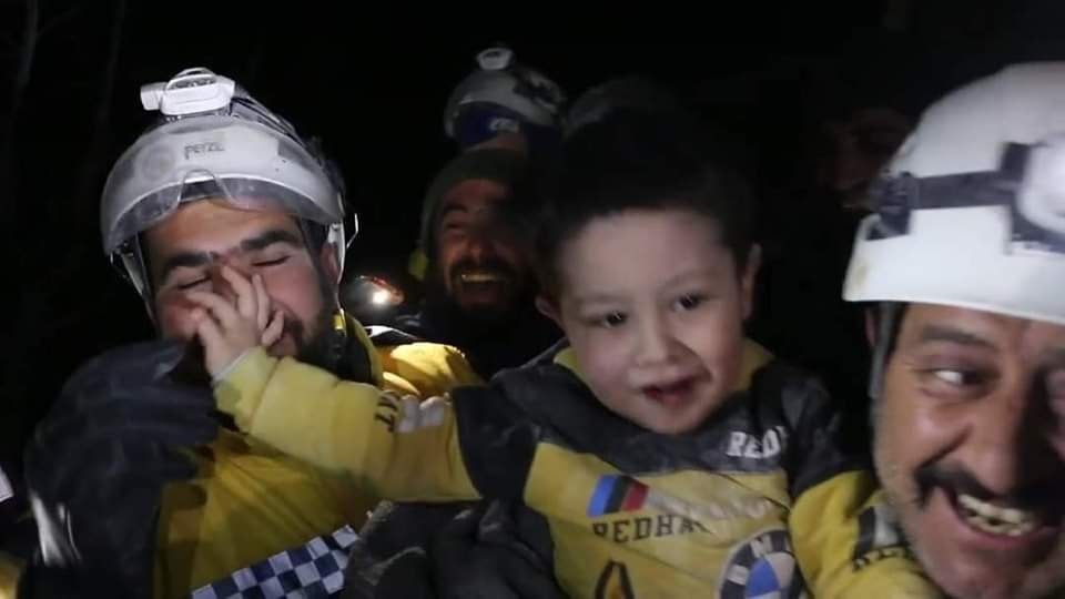 مبتسماً ويداعب من حوله.. هكذا خرج طفل سوري من تحت الأنقاض (فيديو)